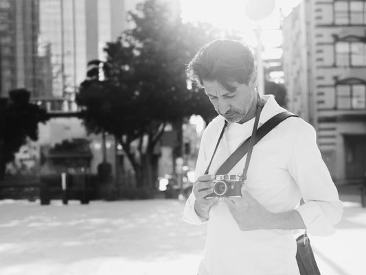 Fotograf trägt Leica Kamera mit schmalem Leder Gurt